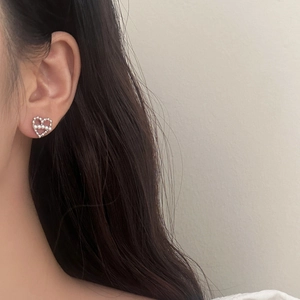 Gros plan de boucles d'oreilles cœur en perles portées par un mannequin en style
