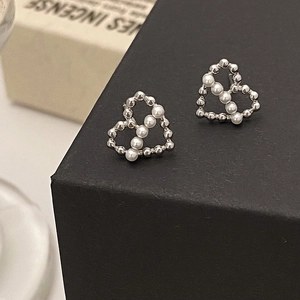Vue macro de boucles d'oreilles cœur en perles argentées sur un écrin noir texturé