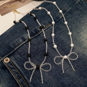 Elegant French style beaded pearl necklace with bow pendants on denim background