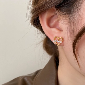 Boucles d'oreilles cœur dorées avec petites perles, portées pour un style élégant