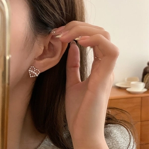 Élégantes boucles d'oreilles cœur creux avec perles portées dans un décor intérieur