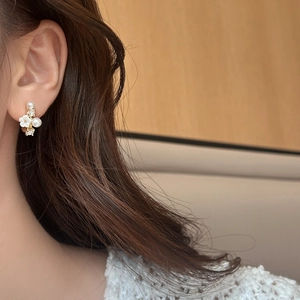 Elegante Blumen-Ohrstecker mit weißen Perlen und Strass auf Goldbasis an einem Modell