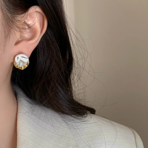 Elegant gold plated irregular geometric earrings with cream finish worn by a model