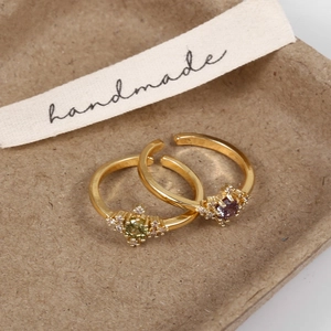 Detailed view of handmade gold-plated rings with emerald and amethyst zircons
