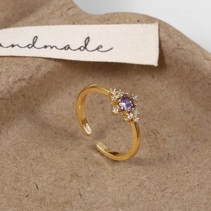 Macro shot of gold adjustable starburst ring with round purple gemstone and white zircons