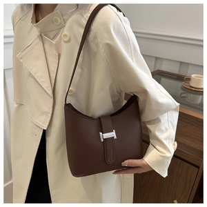 Close-up of brown leather half-moon shoulder bag with silver H-buckle on a trench coat