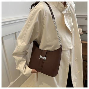 Detail of dark brown leather underarm bag with silver H-buckle and chain strap