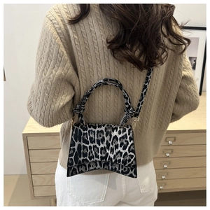 Fashionable leopard print shoulder bag with curved bottom and detachable strap on a model