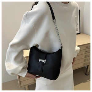 Close-up of black leather handbag with silver H-shaped buckle and metal chain strap