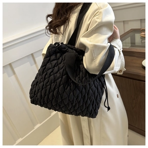 Macro view of black quilted puffer bag texture with wide shoulder strap details