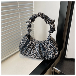 Détail d'un sac à main léopard plissé avec anse froncée sous une lumière naturelle