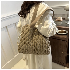 Detail der khakifarbenen gesteppten Puffer-Tasche mit Rautenmuster und Stoffschultergurt