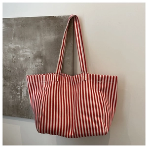 Détail d'un sac cabas en toile à rayures verticales rouges et blanches avec anses