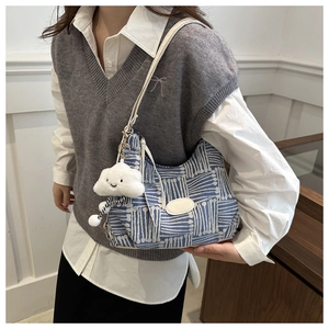 Detail of blue and white plaid knit shoulder bag featuring a fashion tag and plush charm