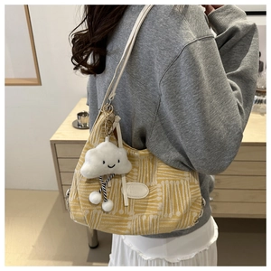 Close-up of yellow textured canvas tote bag featuring a cute cloud plush charm