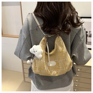 Detail of yellow canvas tote bag with geometric patterns and a soft cloud plush pendant