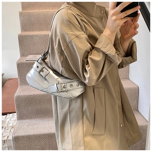Silver Y2K baguette bag with metallic eyelets worn by model in a khaki trench coat