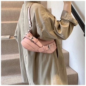 Detail of pink Y2K baguette bag with silver eyelet belts and adjustable shoulder strap