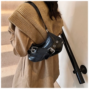 Detail of a shiny black crescent underarm bag with silver buckles on a wooden staircase
