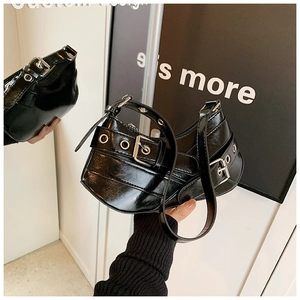 Close-up of black patent leather underarm bag with silver buckles and punk style straps