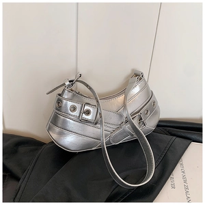 Detail of silver metallic Y2K baguette bag featuring grommet straps and buckle accents