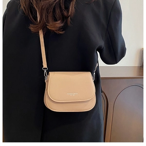 Beige saddle bag with Fashion Trend text worn over a black blazer for office style