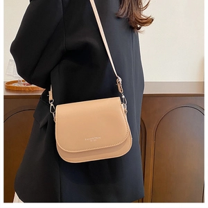 Détail d'un sac besace beige avec bandoulière réglable porté par un mannequin de côté
