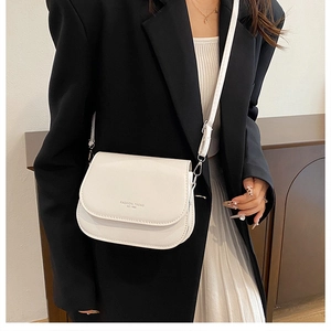 Détail du sac selle blanc avec inscription FASHION TREND sur un blazer noir