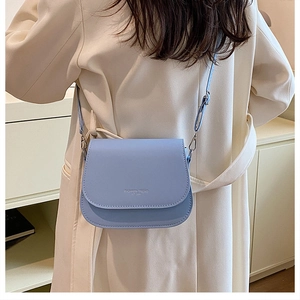 Gros plan du sac besace bleu clair avec bandoulière réglable sur un manteau beige