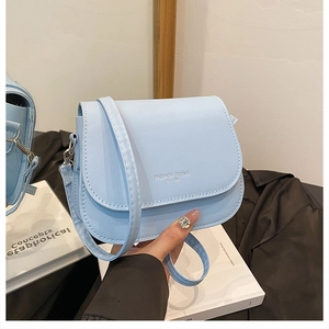 Close-up of light blue saddle bag with Fashion Trend lettering and silver hardware details
