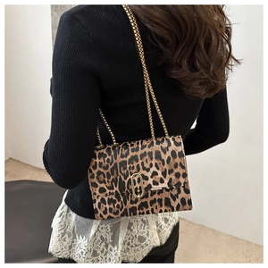 Fashionable leopard print crossbody bag with gold chain strap shown on model shoulder