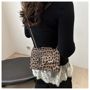 Chic leopard print crossbody bag with gold chain strap shown on model over black sweater