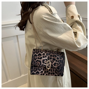 Fashionable leopard print shoulder bag with gold chain strap worn by a model