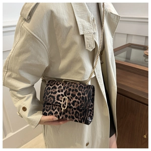 Detail of leopard print crossbody bag with gold chain strap worn with beige coat