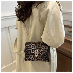 Detailed view of leopard print shoulder bag with gold chain strap on model's beige trench coat
