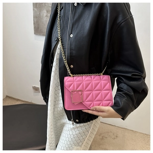 Detail of fuchsia quilted crossbody bag with gold chain strap on a stylish model