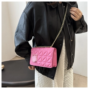 Detail of pink quilted crossbody bag with gold chain strap and metal buckle closure
