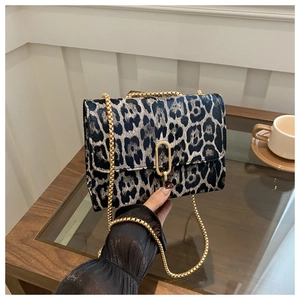 Detailed close-up of leopard print flap bag with gold chain strap and metal lock