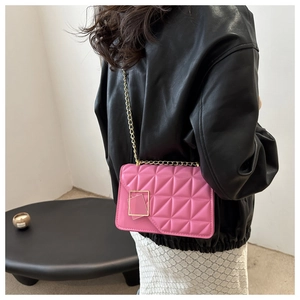 Detail of pink quilted crossbody bag with gold rectangular clasp and chain strap