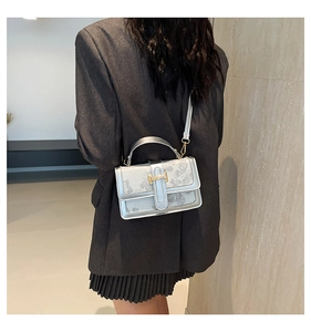 Detail of silver embossed floral shoulder bag featuring a gold H buckle and slim strap
