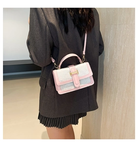 Detail view of pink and white crossbody bag with golden H-buckle on a model