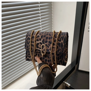 Detail of leopard print crossbody bag with gold U-shaped buckle and metal chain strap
