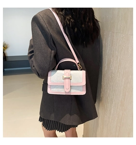 Detail of a pink and blue crossbody bag featuring a golden H-clasp and leather handle