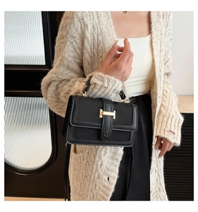 Close-up of black crossbody bag with gold hardware clasp and textured leather detail