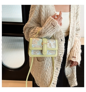 Detail of embroidered landscape pattern and sage green leather on a vintage crossbody bag