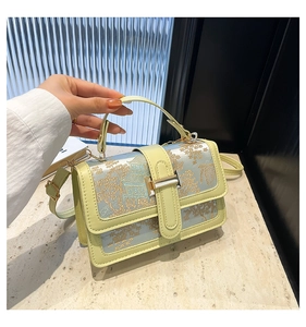 Detail shot of the yellow embroidered handbag featuring mountain patterns and gold clasp