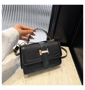 Detailed view of black embossed leather square bag with gold metal clasp and top handle