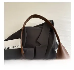 Detailed view of dark brown leather tote with wide handle and tie knot closure detail