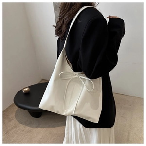 Rear view of a model wearing a white glossy tote bag with minimalist bow detail