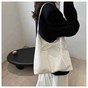 Detailed side view of a white tote bag with bow detail on a shoulder-worn model